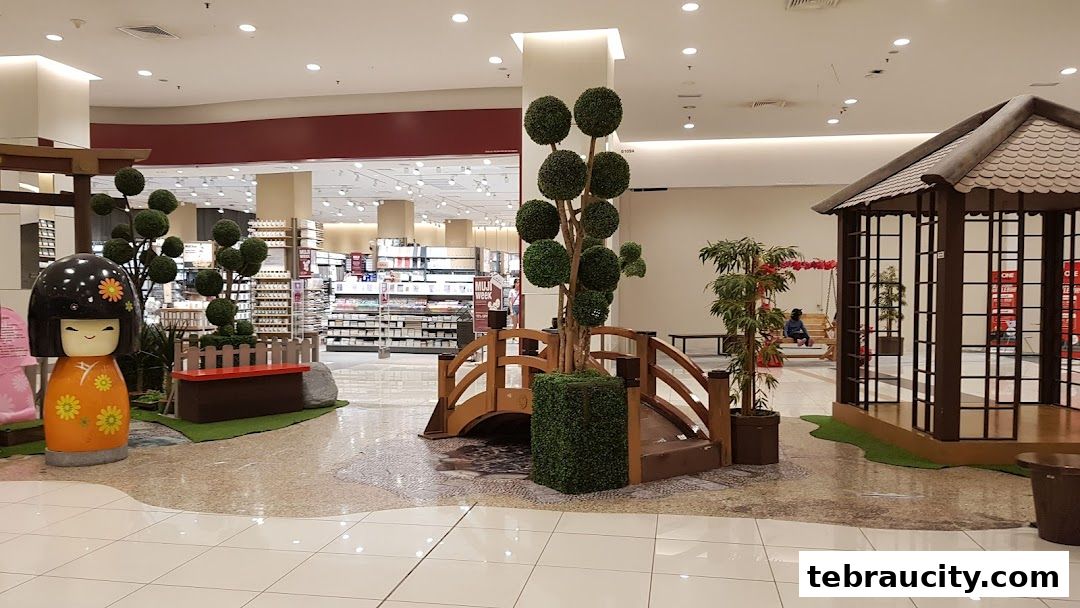 A Japanese-themed display with a kokeshi doll, bridge, and gazebo in a shopping mall.