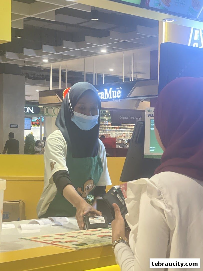 A customer pays at a Potato Corner counter with a staff member assisting.