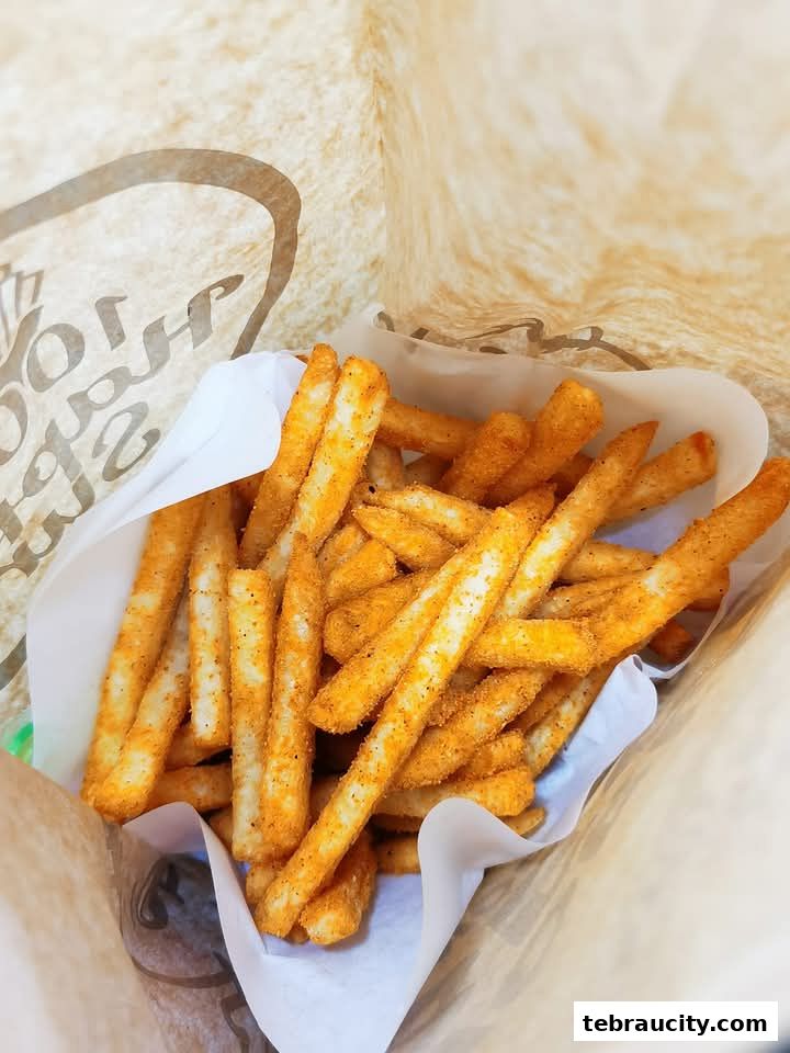 A close-up shot of a bag filled with crispy, seasoned french fries.