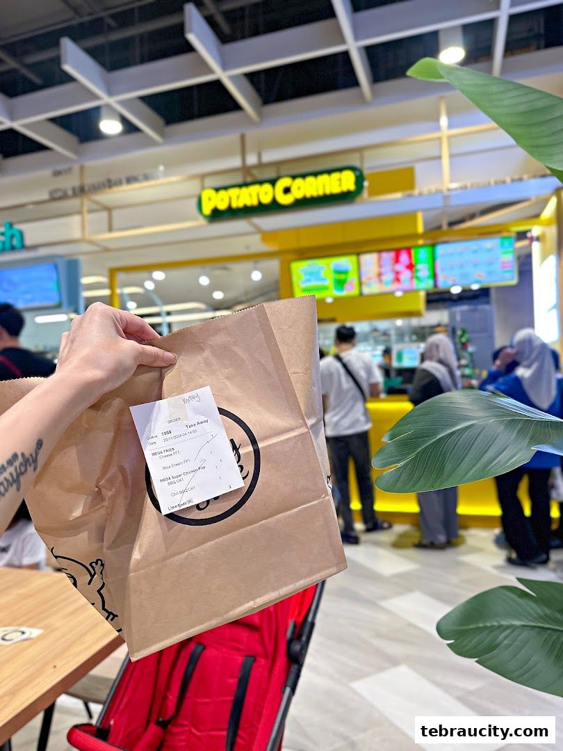 A person holds a Potato Corner takeaway bag in front of the store.