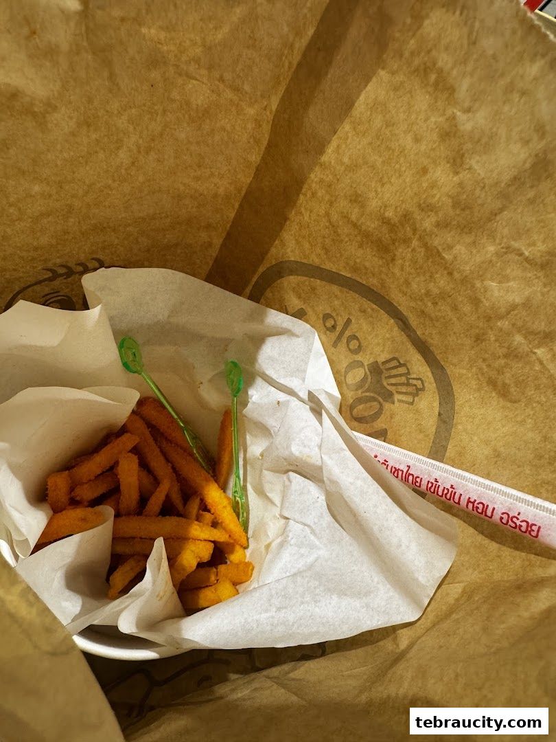A paper bag filled with crispy fries and green toothpicks.