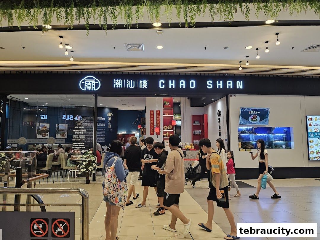 People walking past the entrance of Chao Shan restaurant with its prominent signage and interior visible.