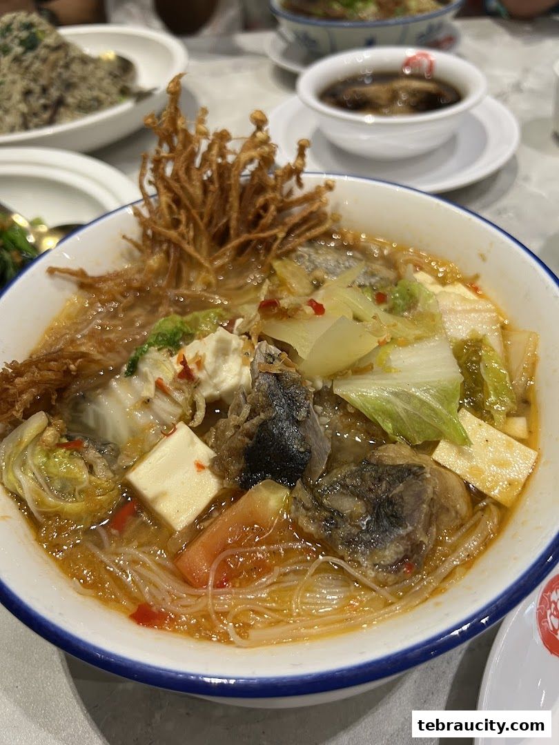 A close-up of a delicious bowl of soup with fish, tofu, vegetables, and noodles.