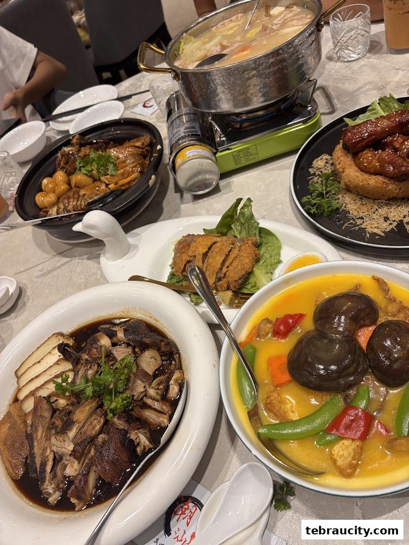 A table laden with various delicious dishes, including a hot pot, braised meats, and a curry dish.