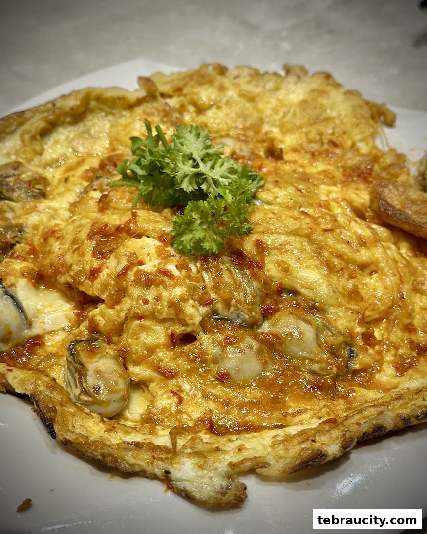 A close-up of a delicious oyster omelet with chili and parsley garnish.