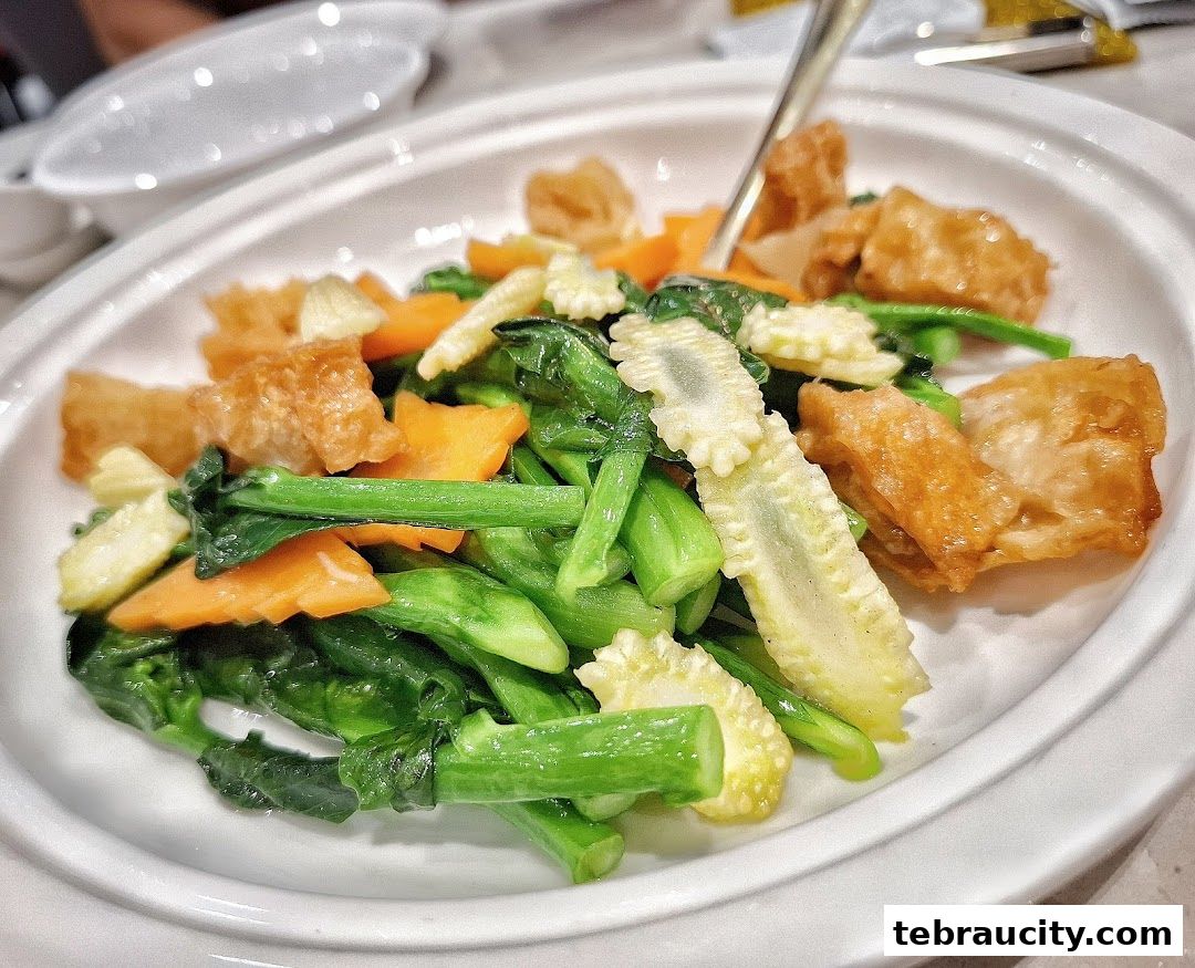 A close-up shot of a delicious stir-fried vegetable dish with baby corn, carrots, and fried tofu.