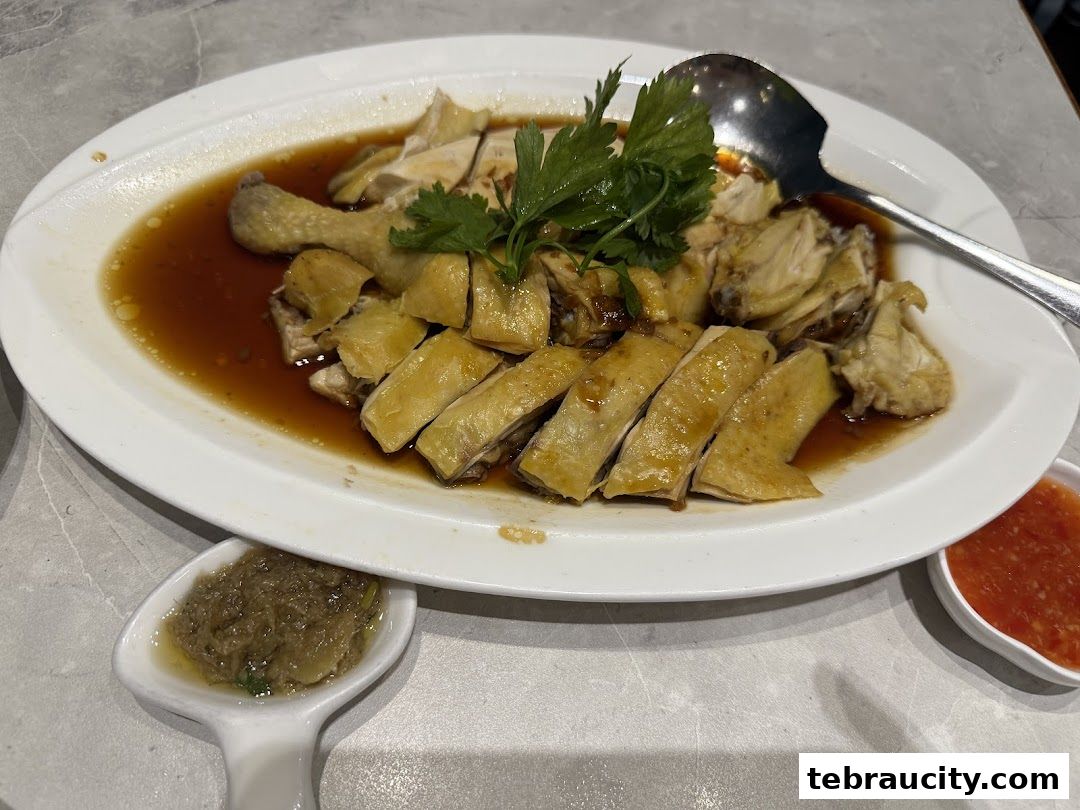 A plate of sliced poached chicken with dipping sauces and a spoon.
