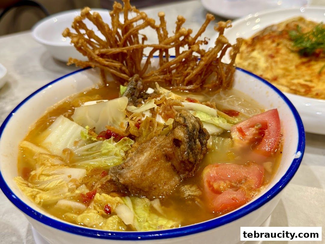 A close-up of a delicious bowl of soup with vegetables, fish, and crispy toppings.