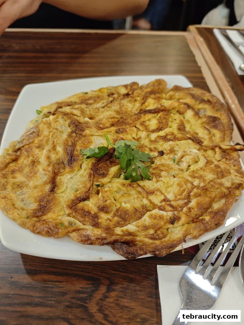 A close-up shot of a golden-brown omelet garnished with fresh cilantro on a white plate.