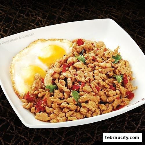 A plate of minced chicken with basil and chili, served with two fried eggs.
