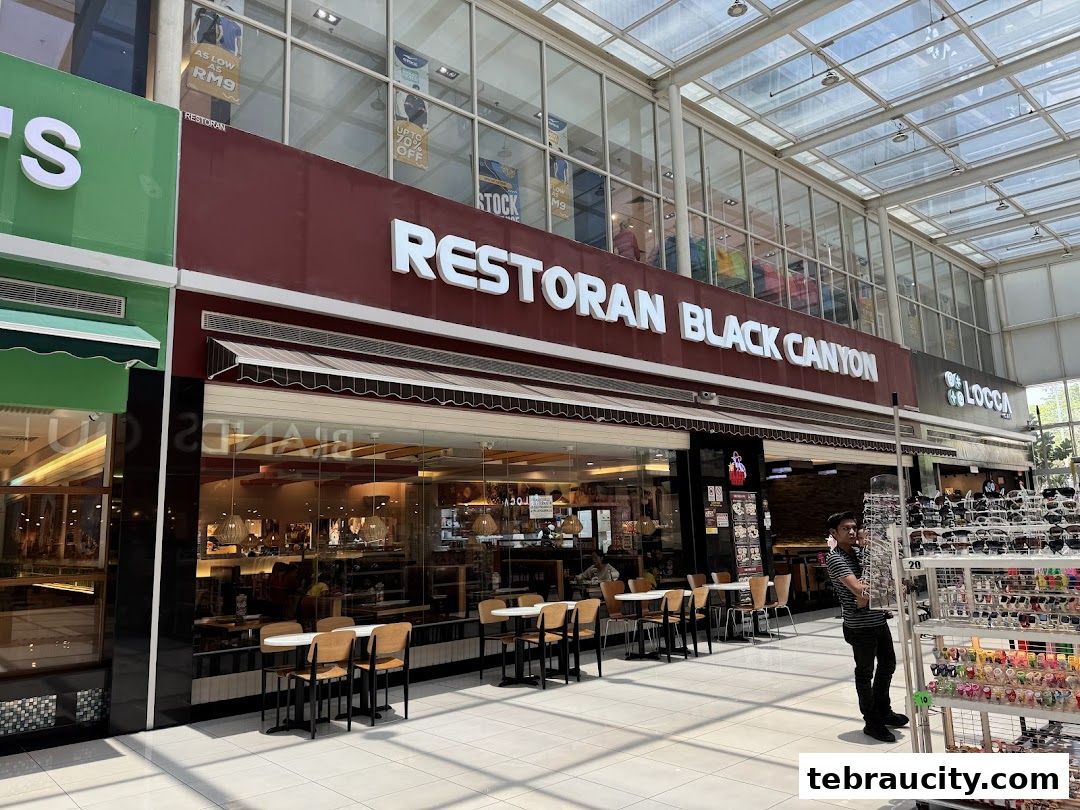 The exterior of Restoran Black Canyon, a restaurant with outdoor seating and a display of sunglasses nearby.