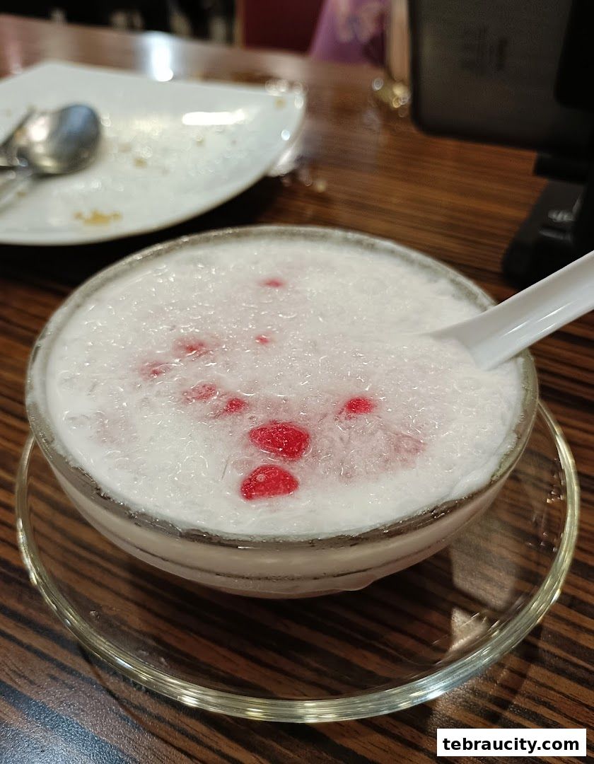 A refreshing dessert with shaved ice, coconut milk, and red jelly pieces, served in a bowl.