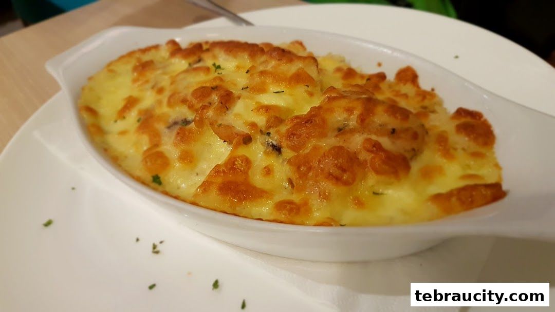 A close-up shot of a creamy, cheesy baked dish topped with herbs.