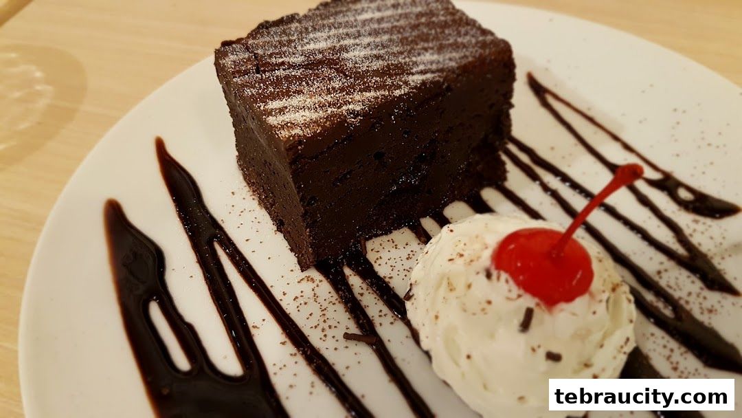 A rich chocolate cake slice served with vanilla ice cream and a cherry on top.