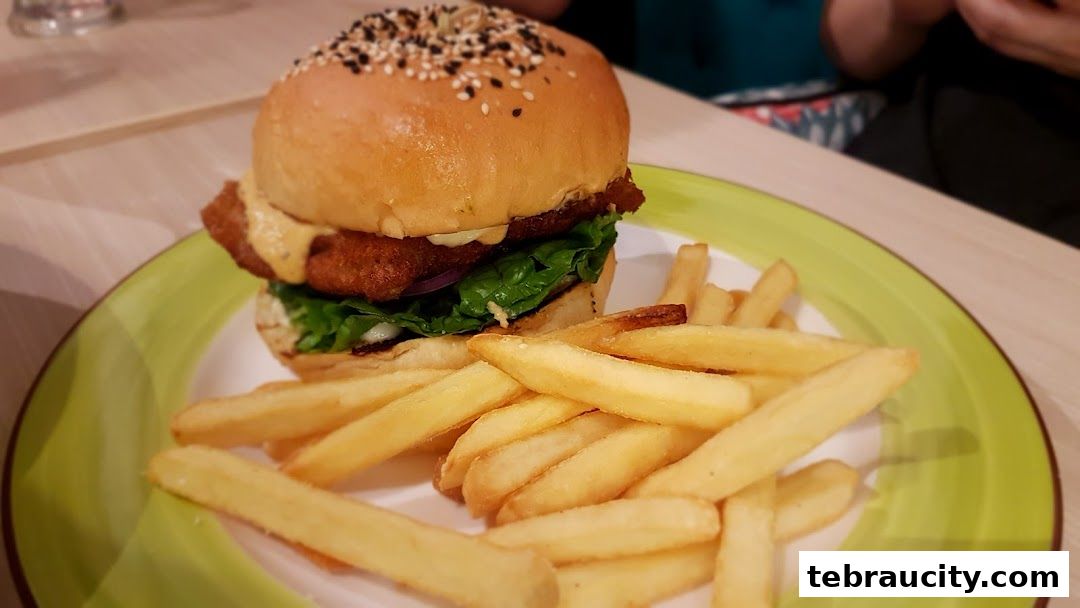 A delicious burger with crispy fries served on a green plate.