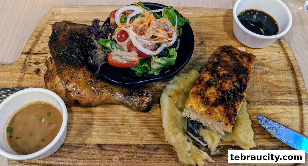 A grilled chicken leg, salmon fillet, mashed potatoes, salad, and dipping sauces served on a wooden board.