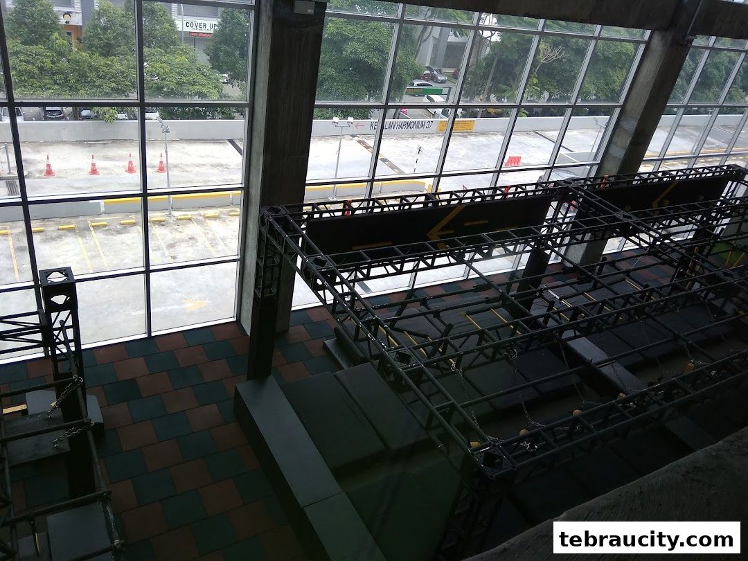 Indoor obstacle course with metal structures and padded flooring, viewed from above.