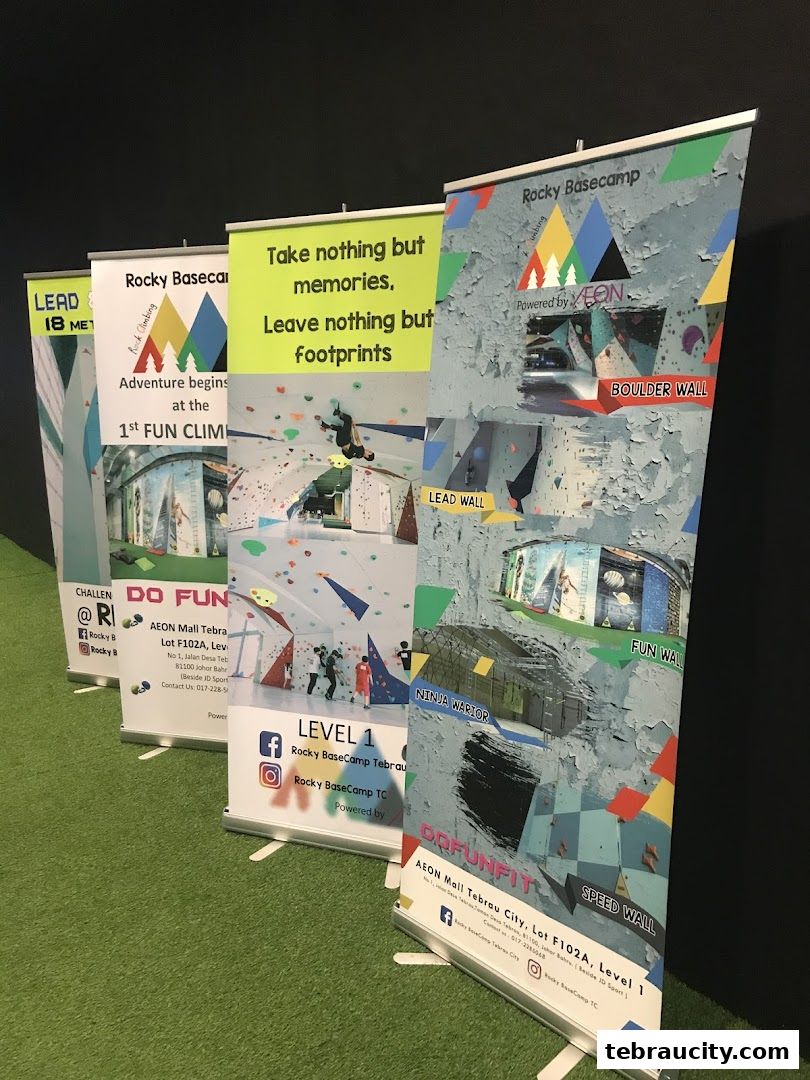 Several promotional roll-up banners for a climbing gym are displayed on a green surface.