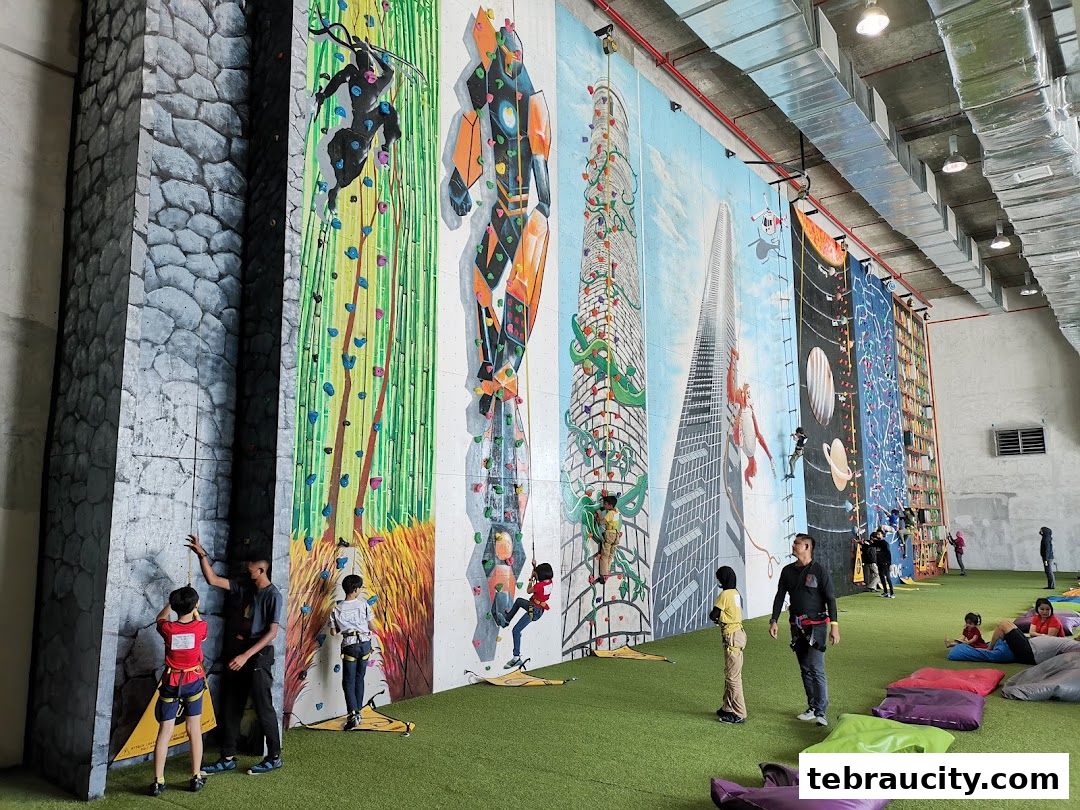 People climbing on colorful, themed indoor climbing walls with beanbags on the floor.