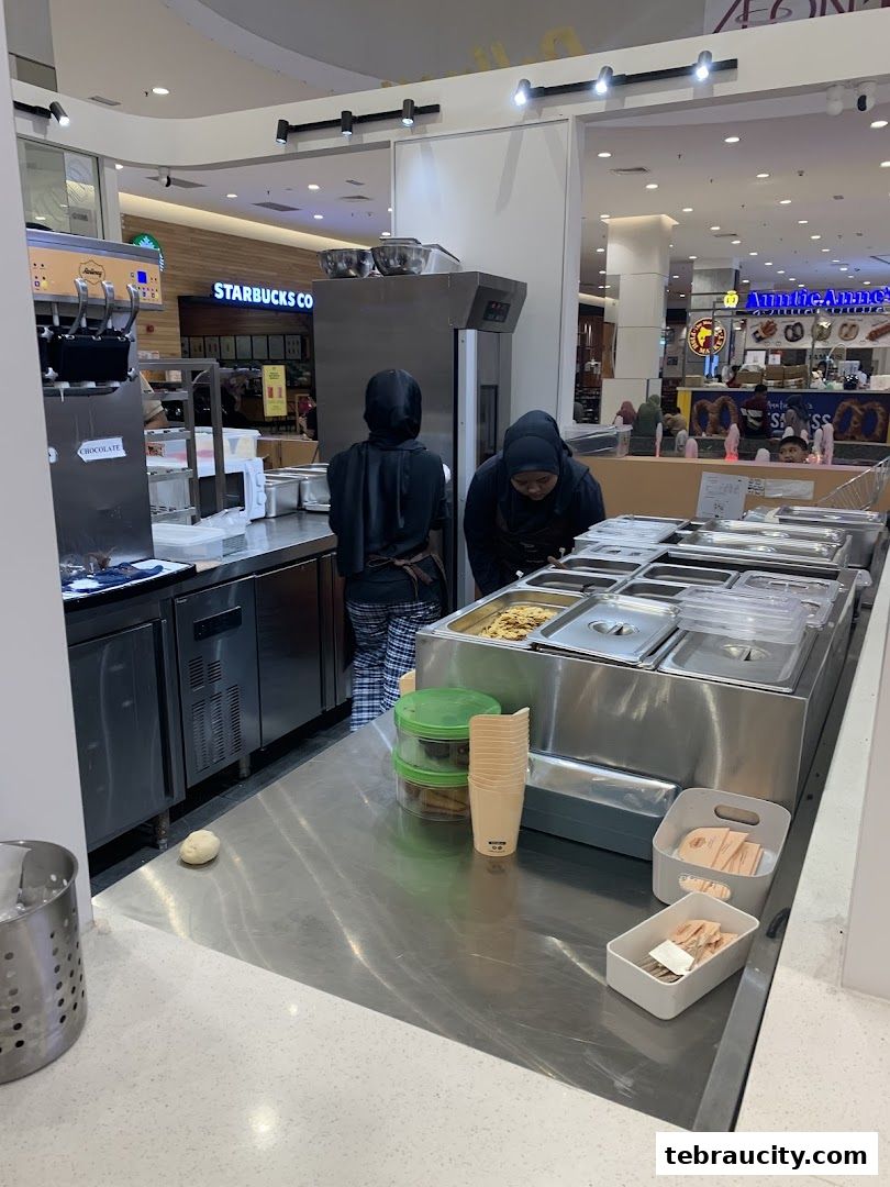Two staff members working behind a counter with food preparation equipment.