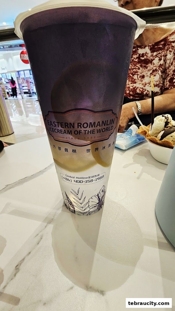 A close-up of a large purple ice cream and tea drink with the brand logo visible.