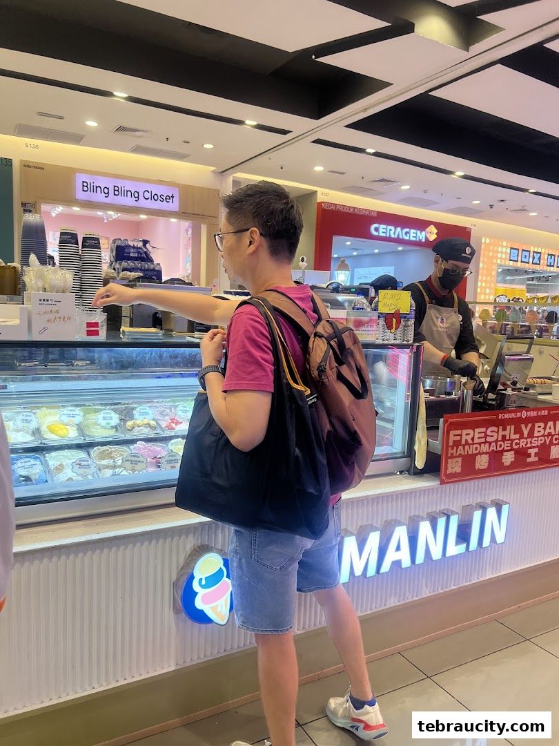 A man is choosing ice cream at a Romanlin ice cream and tea shop in a mall.