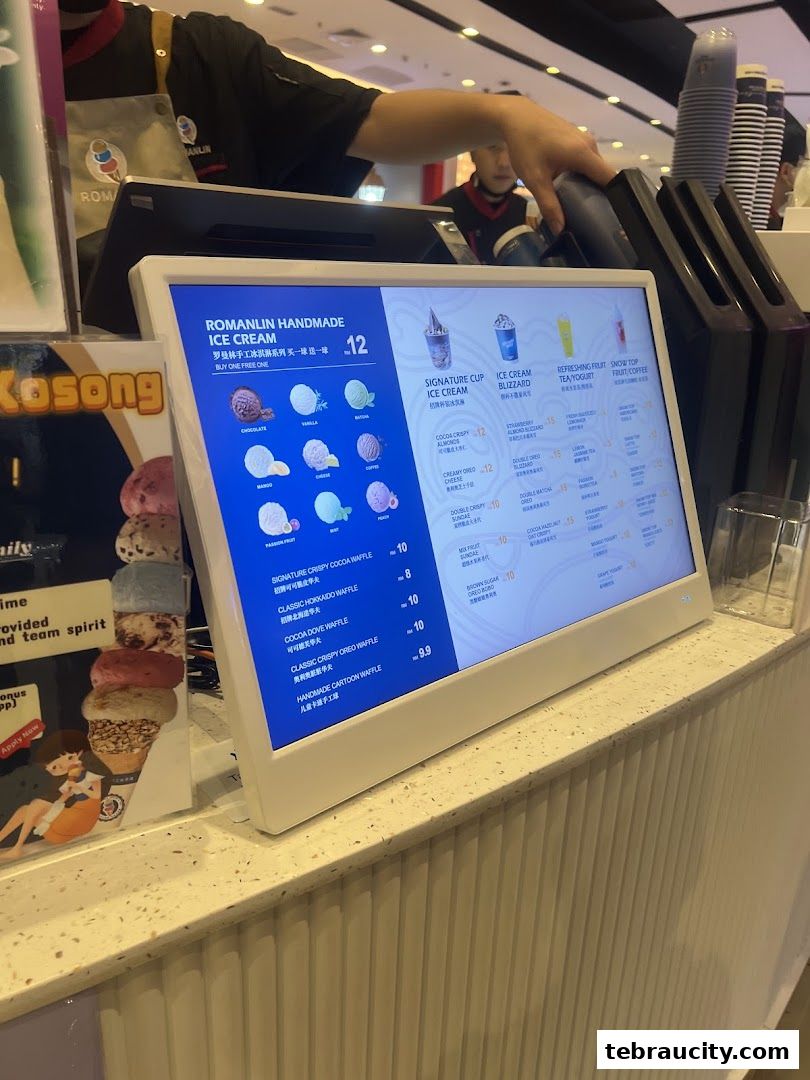 A digital menu board displays various ice cream and tea options with prices.