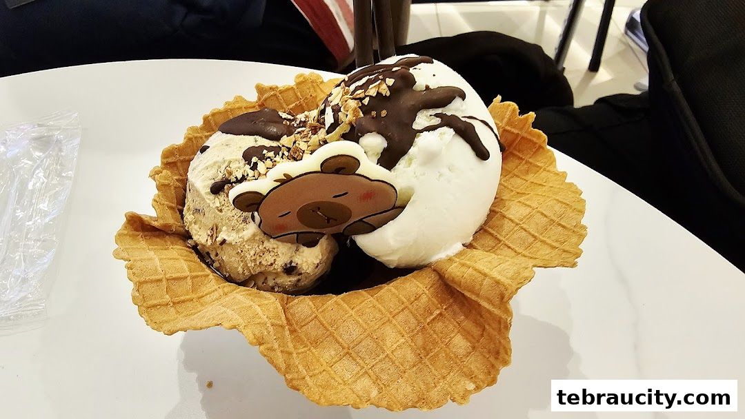 A delicious ice cream sundae served in a waffle cone with chocolate drizzle and a cute bear decoration.
