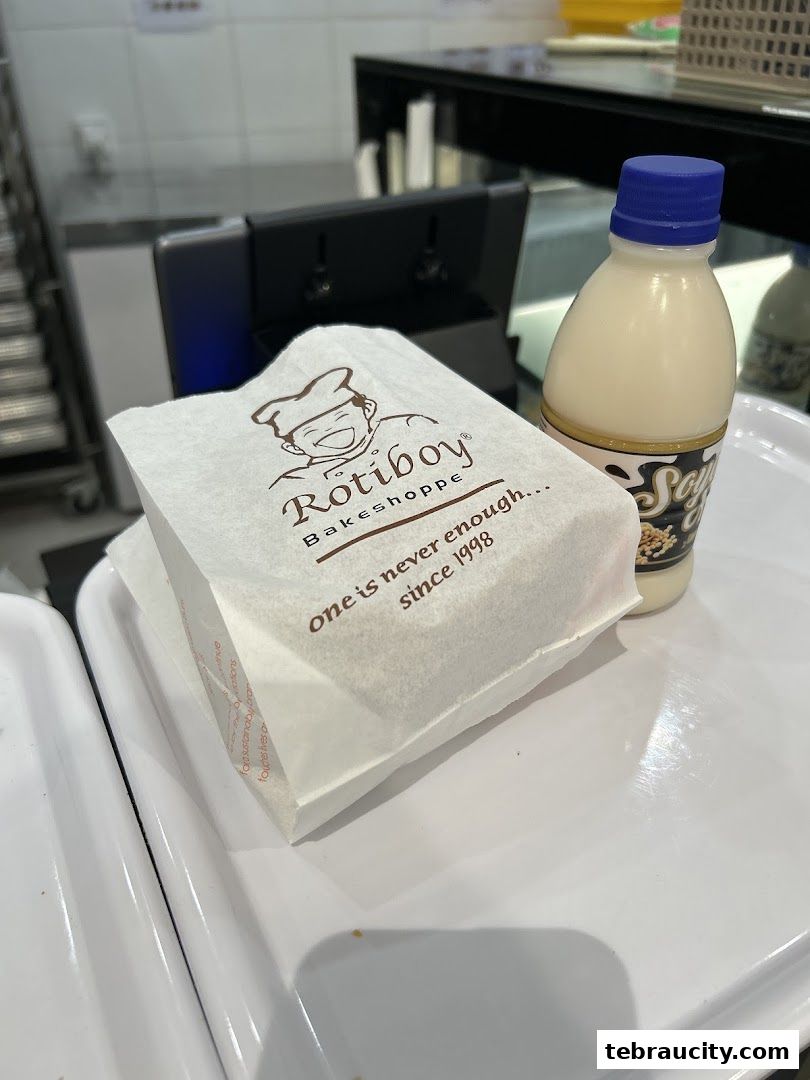 A Rotiboy paper bag and a bottle of soy milk on a white tray.
