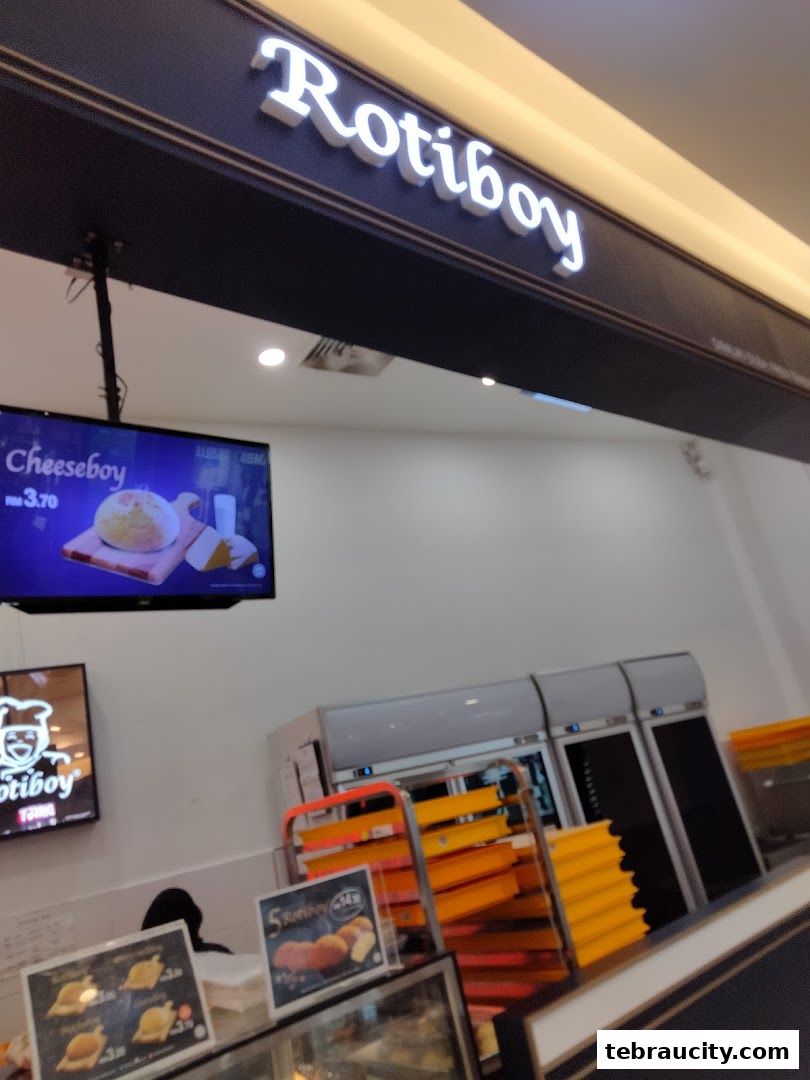 The Rotiboy shop interior with a display screen showing a Cheeseboy and baked goods.