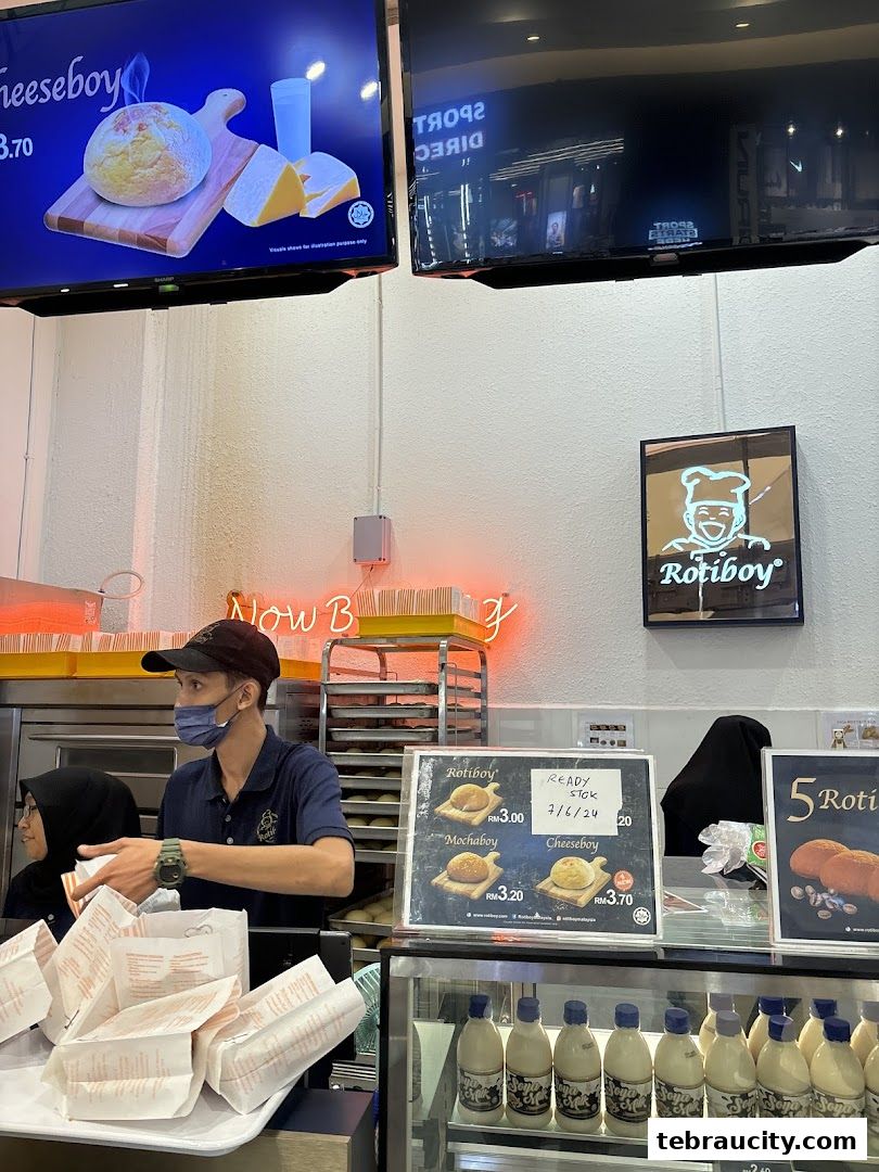 A Roti Boy shop interior with staff serving customers and displaying baked goods and drinks.