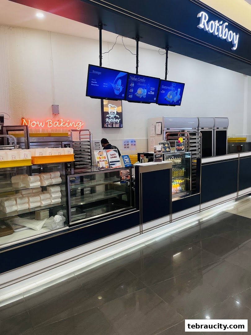 A Roti Boy bakery counter with digital menus displaying food and drinks.