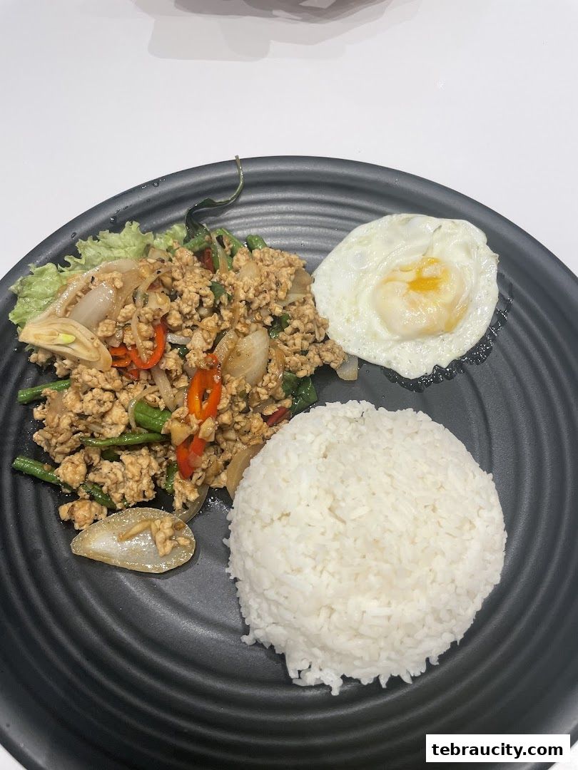A plate of Thai basil stir-fry with minced chicken, served with rice and a fried egg.