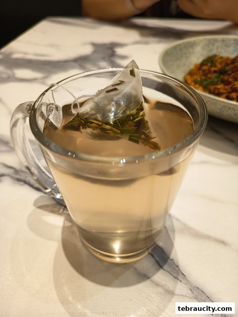 A close-up shot of a clear glass mug filled with tea and a tea bag.