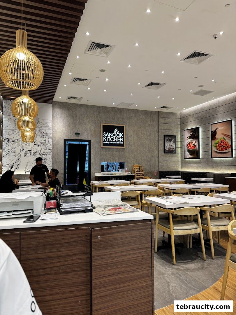 Interior view of Sanook Kitchen restaurant with tables, chairs, and decorative lighting.