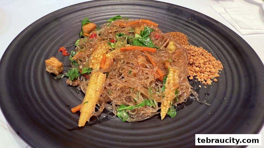 A close-up of a delicious glass noodle dish with vegetables and crushed peanuts.