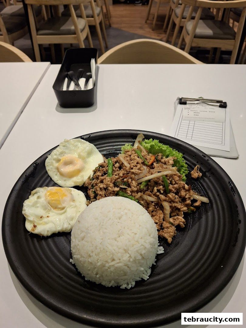 A plate of Thai basil minced chicken with rice and fried eggs, served at Sanook Kitchen.