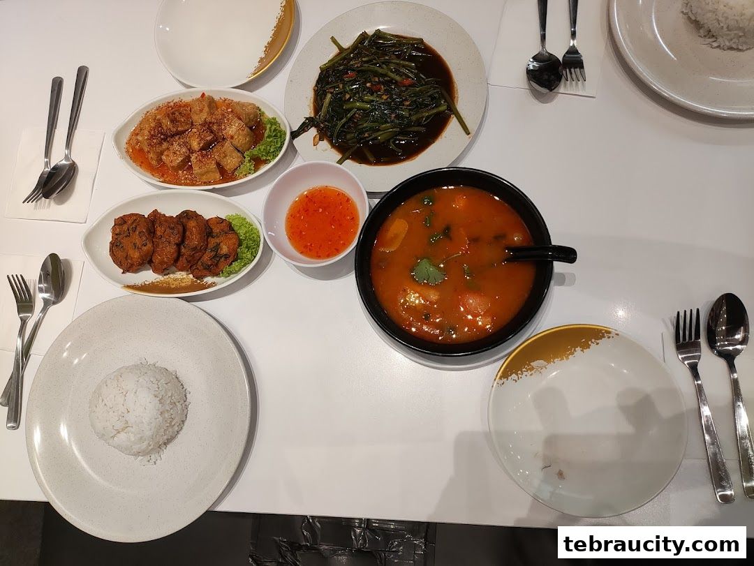 A table laden with various Thai dishes, including soup, fried items, and vegetables.