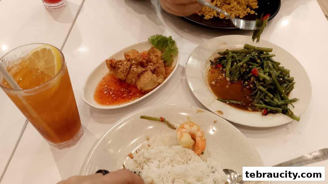 A table setting with various Thai dishes and a refreshing drink.