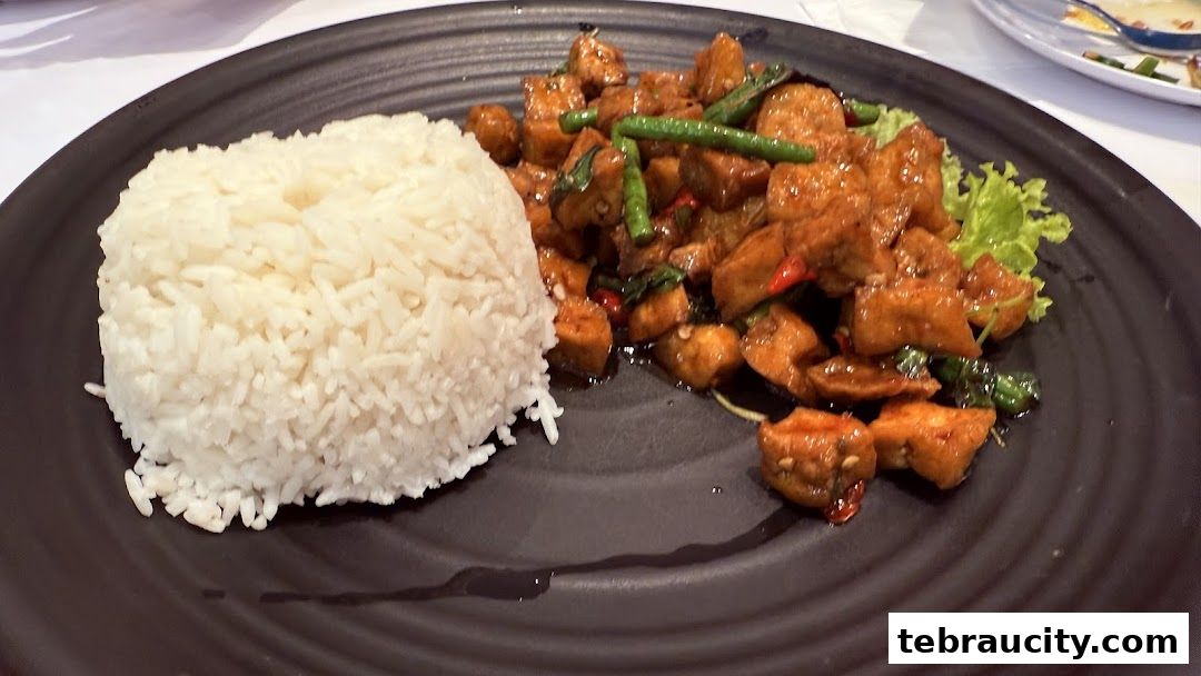 A plate of stir-fried tofu with green beans and rice, garnished with lettuce.