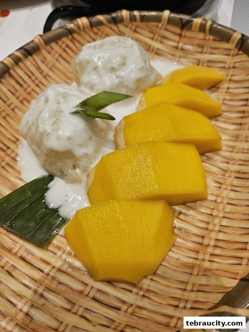 A close-up of mango sticky rice served in a woven basket with coconut milk.