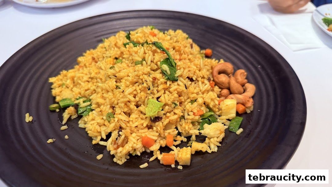 A plate of fried rice with cashews, vegetables, and a hint of spice.