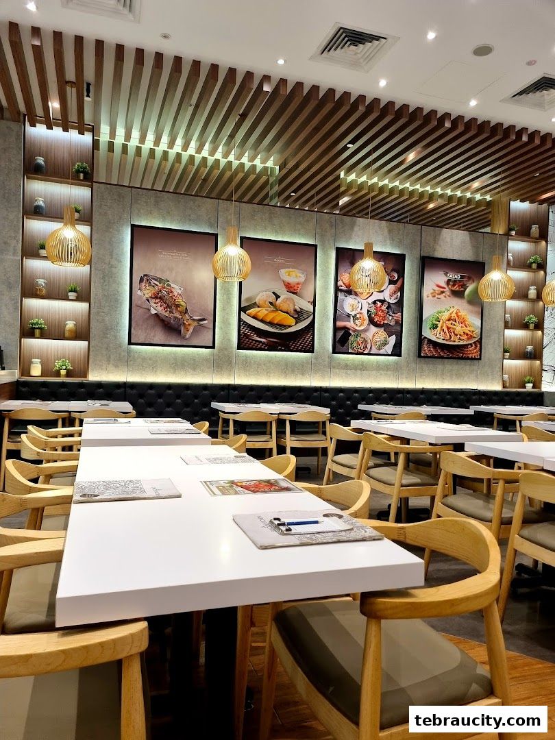 Interior of Sanook Kitchen restaurant with white tables, wooden chairs, and decorative wall art.