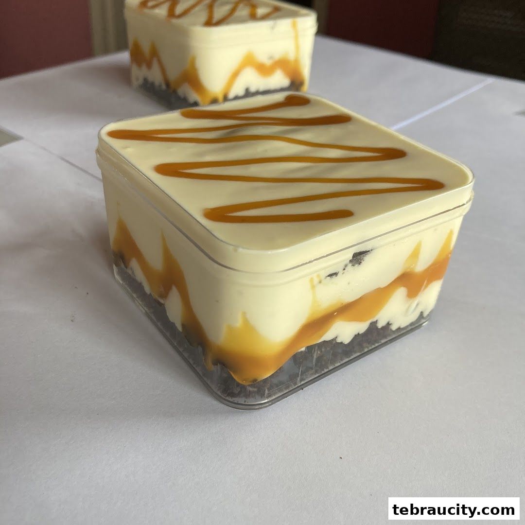 Two clear containers filled with layered dessert, topped with caramel sauce.