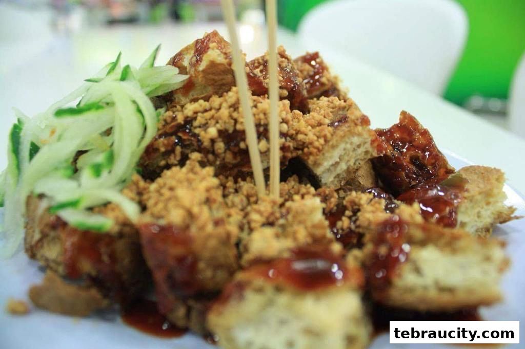 A close-up of fried tofu with sauce, crushed peanuts, and shredded cucumber.