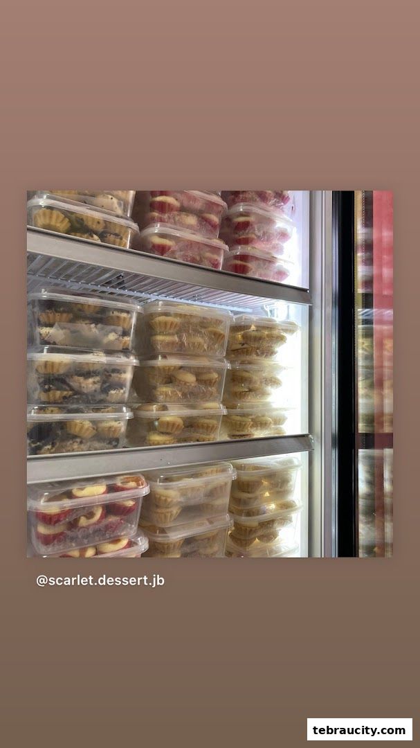 A refrigerator filled with various pre-packaged desserts, including tarts and cupcakes.