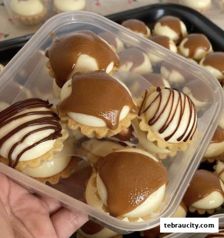 A close-up shot of delicious mini tarts with white cream and caramel or chocolate drizzle.