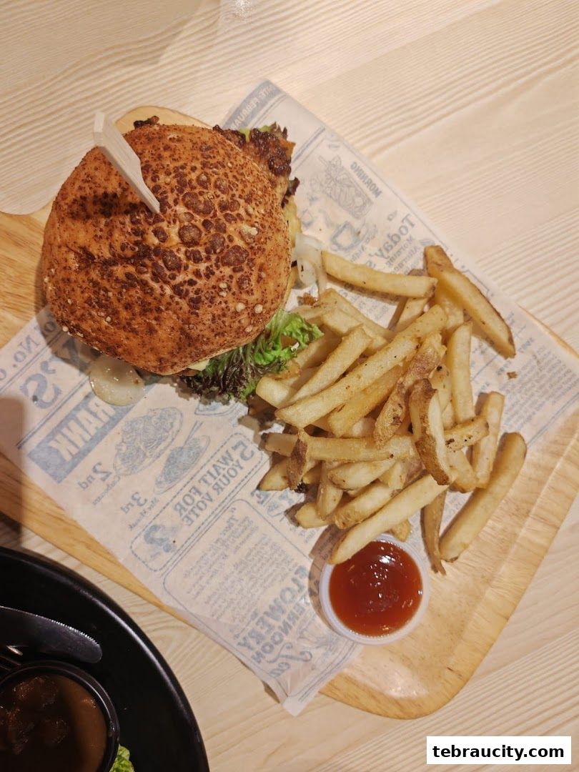 A delicious burger and fries served on a wooden board with a side of ketchup.
