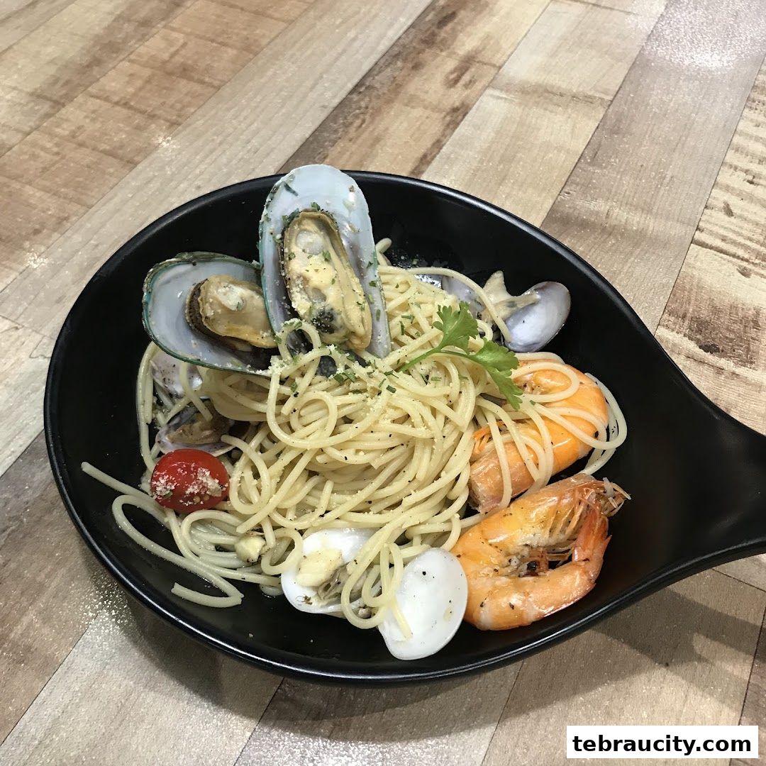 A black bowl filled with spaghetti, mussels, clams, shrimp, and cherry tomatoes.