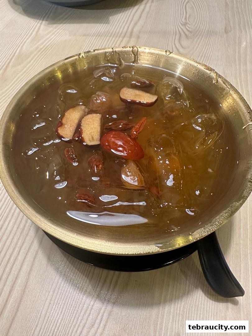 A close-up of a refreshing drink with ice, red dates, and other dried fruits.